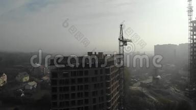 鸟瞰站在<strong>居民楼</strong>旁雾中的塔吊。飞过工地。无人机